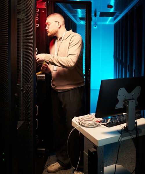 Person working in a data center managing servers and equipment Among servers and cables, person maintaining system functionality and performance