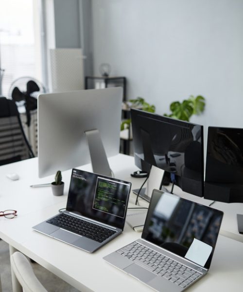 Part of openspace office with group of laptops and computer monitors on workplace of contemporary diversity programmers
